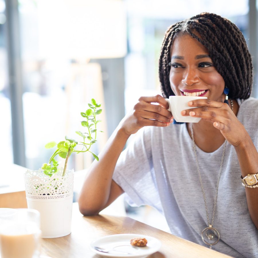 Beautiful young african woman enjoying a cup of coffee in coffee shop